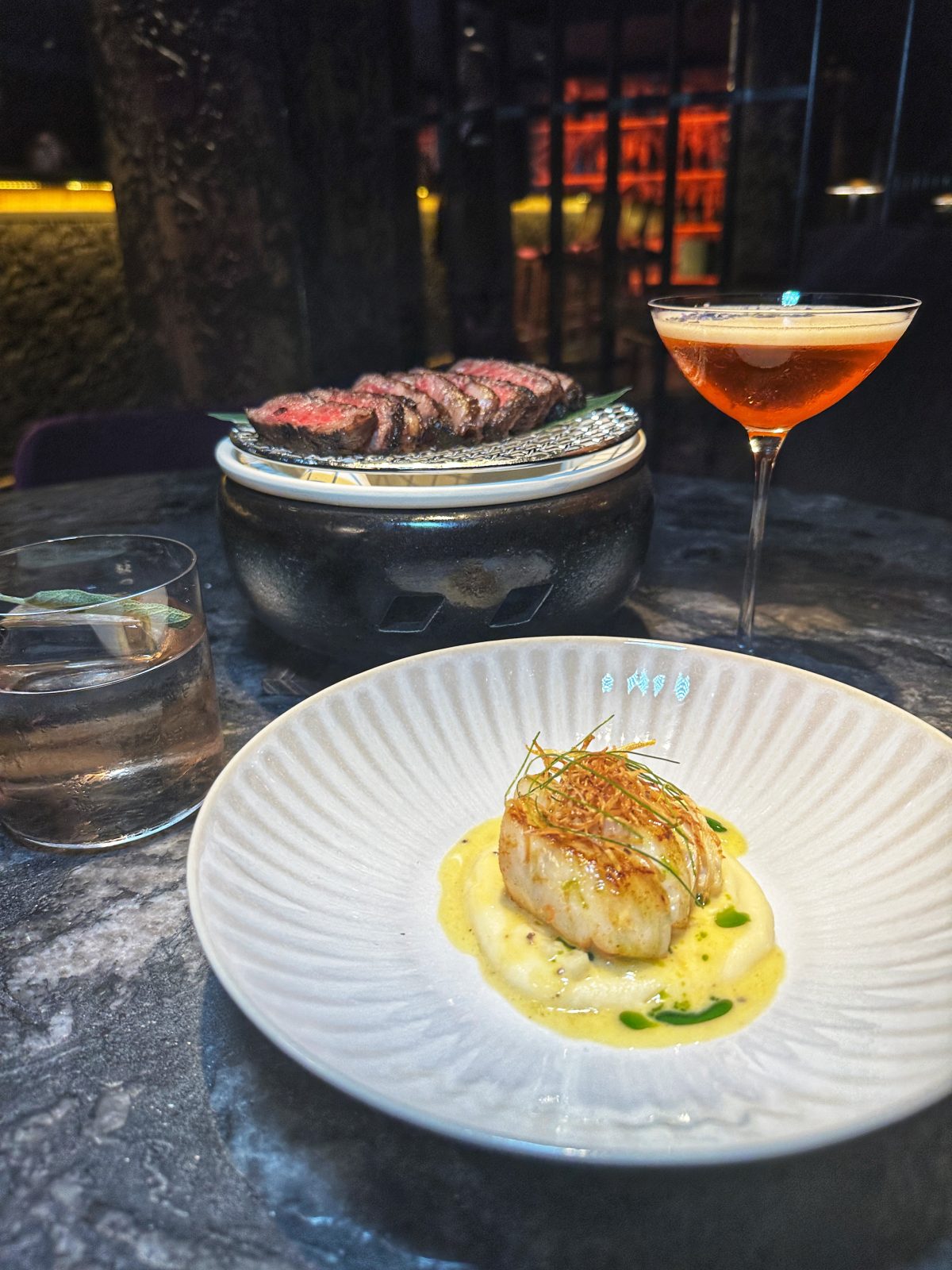 fish with yellow sauce and an orange cocktail in the background.