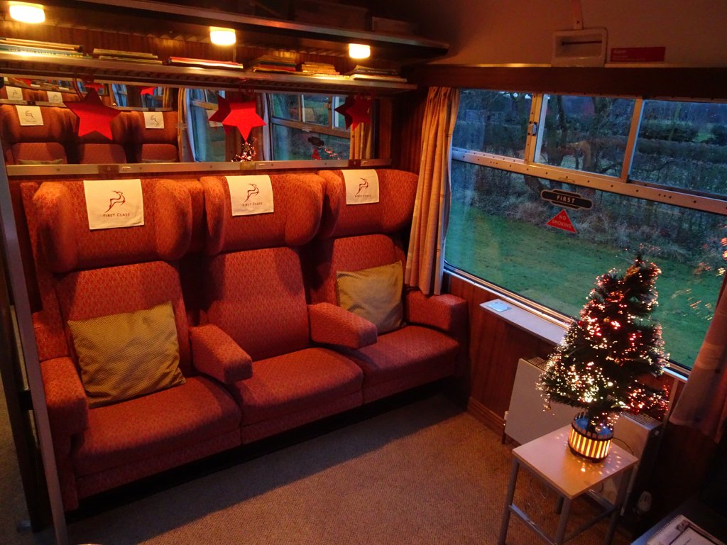 three train seats with red carpet and Christmas tree.