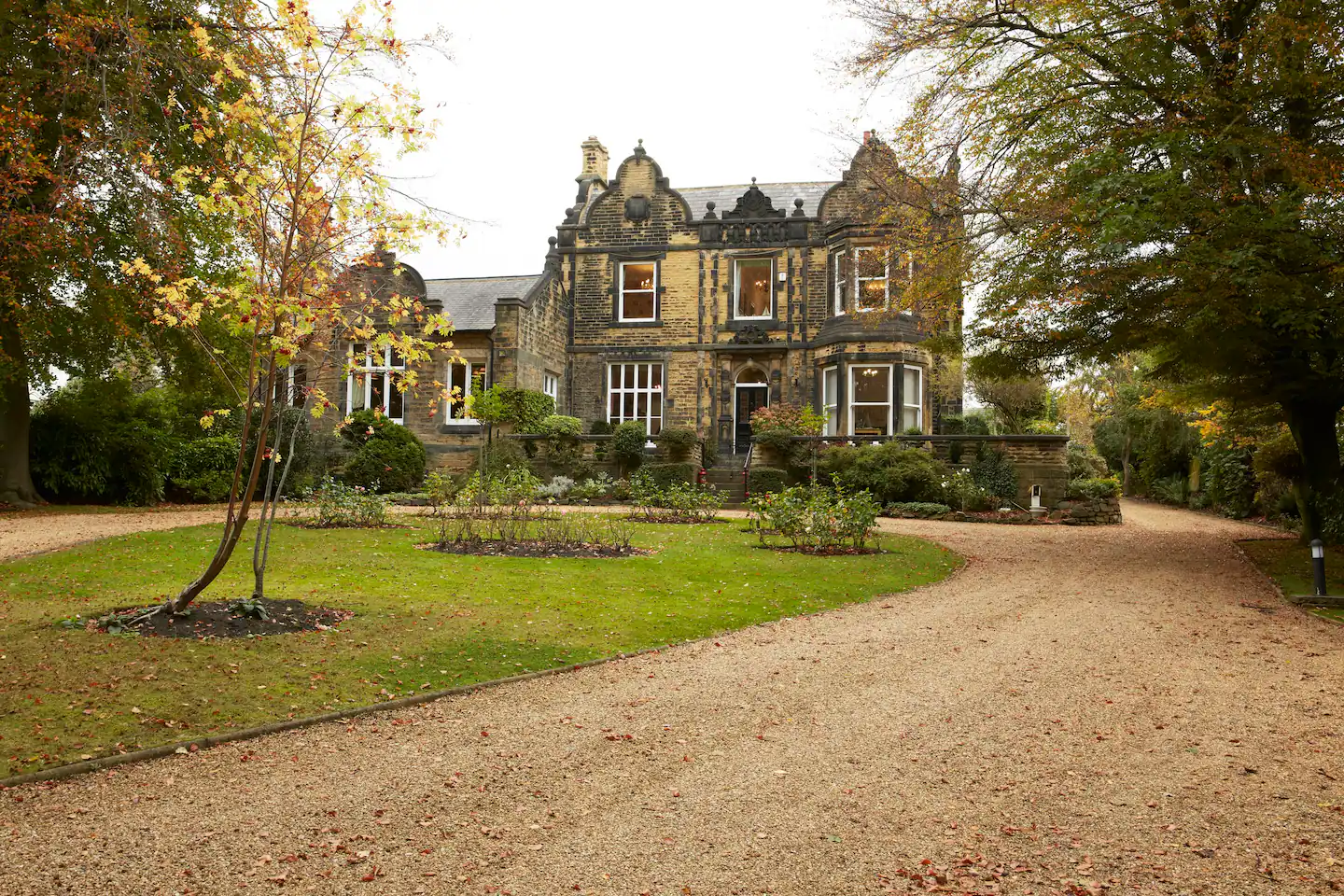 Exterior of a Victorian mansion with five windows and a black door. There is gravel and grass leading up to the house on the driveway.