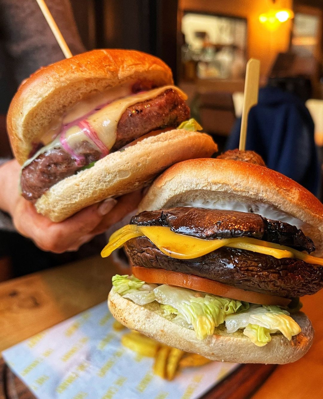 two burgers held to camera.