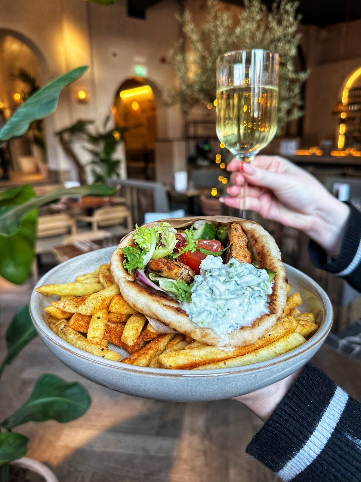 gyros wrap and chips with a glass of wine in the background.