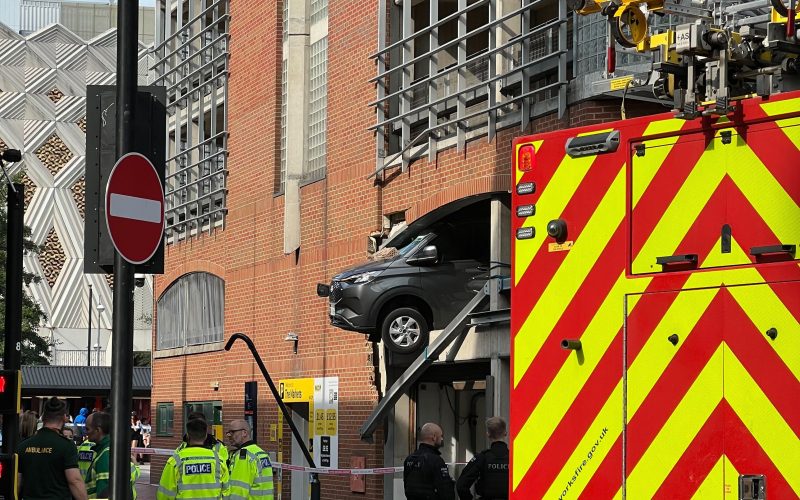 Large cordon in place after vehicle crashes through wall and dangles over Leeds street