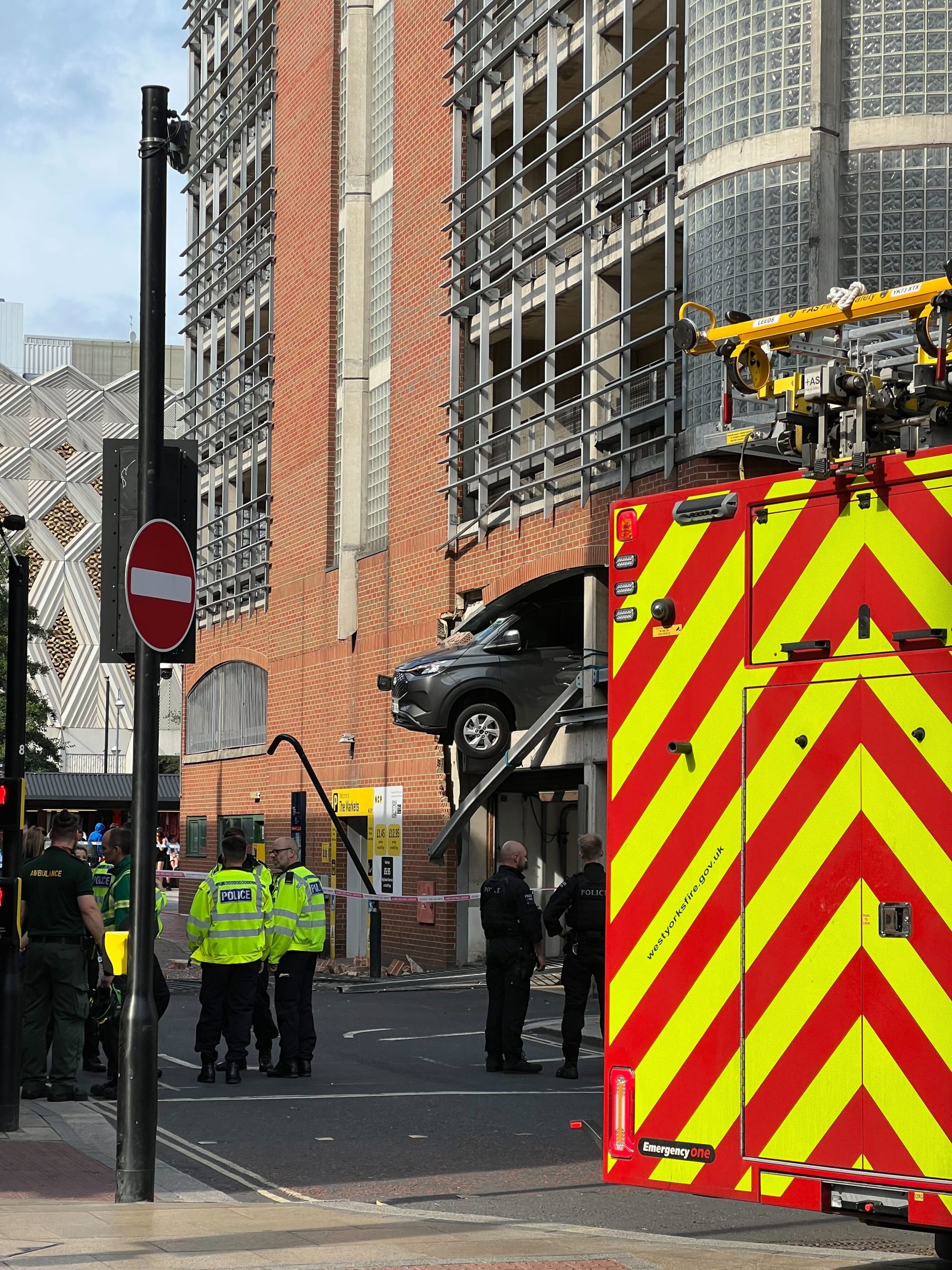 Large cordon in place after vehicle crashes through wall and dangles over Leeds street