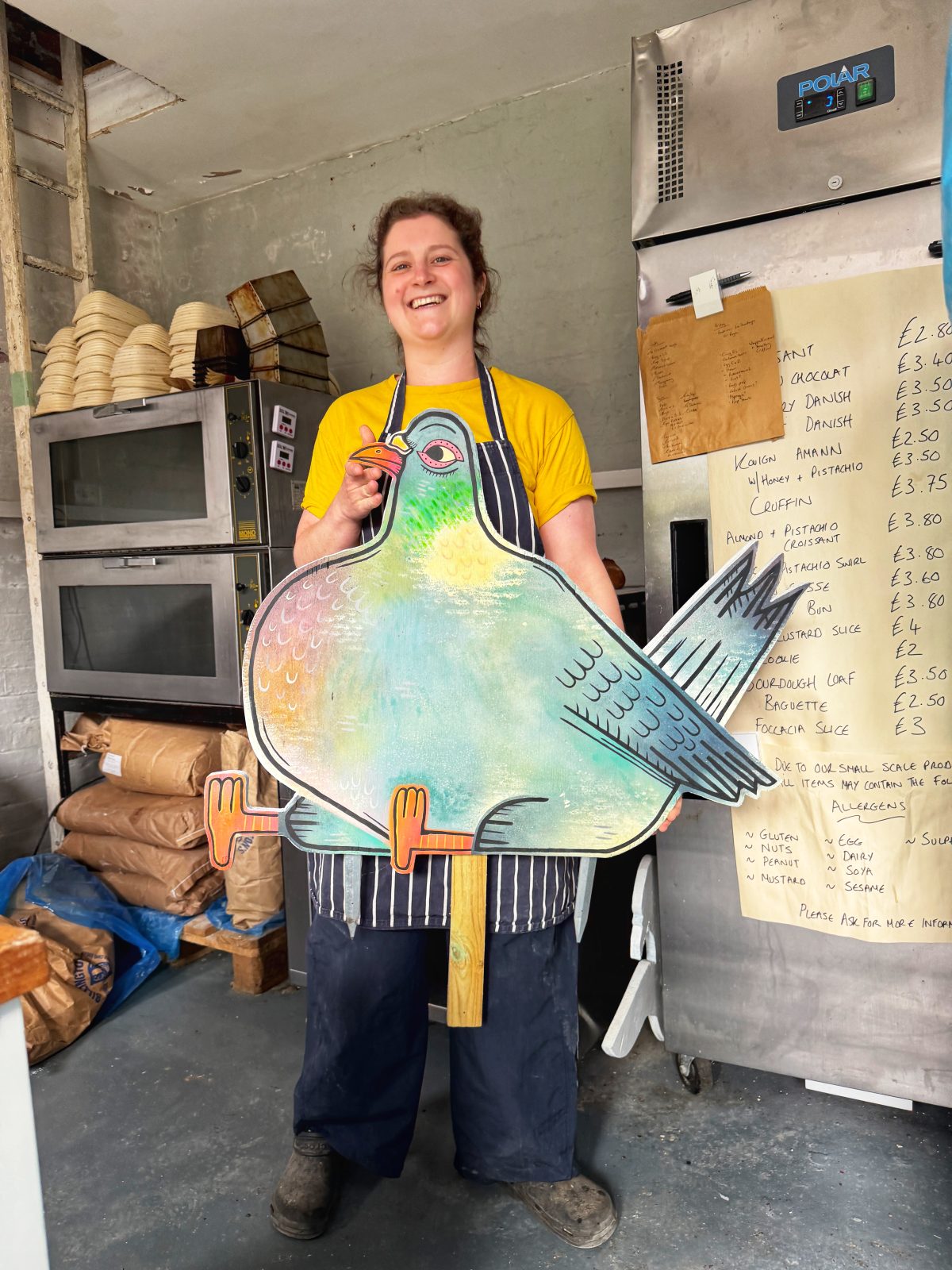 Ruth posing with a pigeon statue alongside some of her delicious golden creations / Image Credits: The Hoot Leeds / The Fat Pigeon